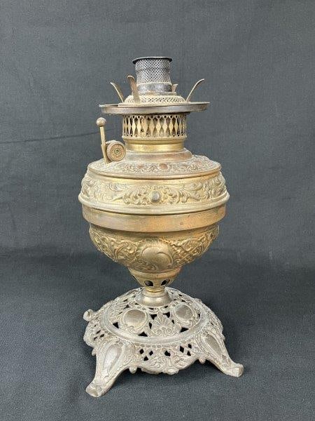 Matthews & Willard Brass Oil Lamp: A brass oil lamp by Matthews & Willard featuring intricate scrollwork on the fittings and base. The top is marked M & W 95 denoting the maker. Measures approximately 12 3/4" H x 9" in diameter. Shows