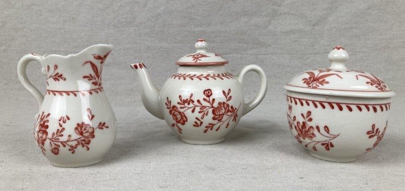 Williamsburg Tea Service: Three tea service dishes, includes teapot, creamer pitcher, and covered sugar bowl, attributed to Andrea by Sadek. White porcelain with red floral pattern, stamped Williamsburg on the bottom, part of