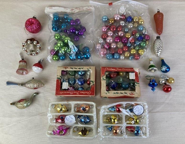 Vintage Glass Christmas Ornaments: Festive assortment of vintage glass Christmas ornaments including a fish, a goose, reflector-style pieces, and multicolored spherical ornaments. Displaying a charming aged patina, the group features v