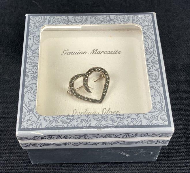 Sterling Silver and Marcasite Heart Brooch: Delicate heart-shaped brooch adorned with numerous faceted marcasite stones that lend a refined sparkle to its curving form. Marked 925 for sterling content. Measures approximately 1" H x 1" W. In goo