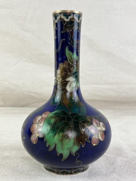 Chinese Cloisonne Vase: Elegant vase featuring a deep cobalt blue ground adorned with green leaves and pink fruit clusters, finished with gold-toned rim and base. Stamped. Measures approximately 6 7/8" H x 3 3/4" W x 3 3/4"