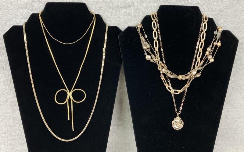 Five Gold Tone Necklaces: Grouping of five gold tone necklaces in varied and distinctive styles, including a standout pendant featuring a saintly bust with a sword, a strand accented with faux coin bronze pearls, and a lariat-