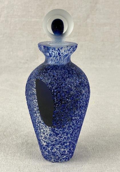 High-Quality Art Glass Perfume Bottle: A high-quality art glass perfume bottle featuring rich cobalt blue tones with a speckled surface and a graceful, curving form. Measures approximately 6″ H x 2 1/2″ in diameter. In good con