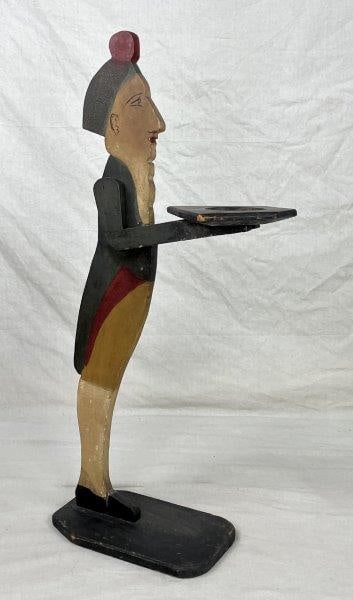 Folk Art Calling Card Holder: A striking folk art calling card holder in the form of a polychrome-painted figure dressed in historical attire, holding a tray for cards. The figure features handsomely painted facial details and str
