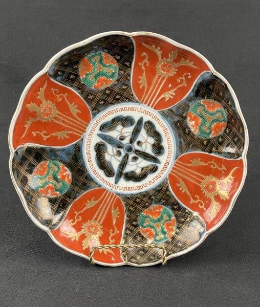 Japanese Imari Plate: A Japanese Imari plate decorated in characteristic vibrant cobalt blue, iron-red, and green tones, displaying a traditional palette and balanced decoration with a scalloped edge. Measures approximatel