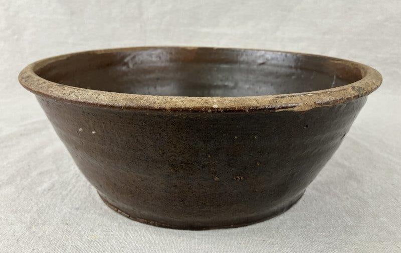 Southern Stoneware Bowl: A Southern stoneware bowl of robust form, finished in a dark Albany slip glaze. The bowl displays strong utilitarian character with natural surface variation from firing. Measures approximately 4 1/8&