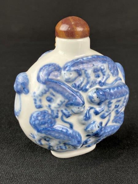 Chinese Dragon Blue and White Snuff Bottle: A porcelain Chinese snuff bottle decorated in blue and white with embossed dragon motifs, dating to the Qing dynasty. The bottle features reign marks to the base and displays strong relief work with t