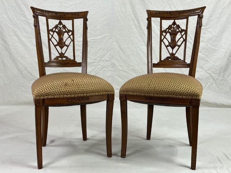 Pair of Ornately Carved Fruitwood Chairs with Saber Legs: A decorative pair of urn splat chairs featuring ornately carved splats with floral motifs and graceful saber legs. The refined forms reflect classic period styling and careful craftsmanship. One chair