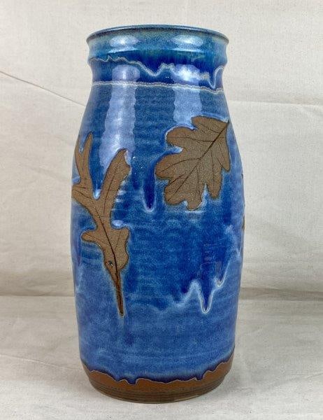 Smoky Mountain Pottery Vase: A pottery vase by Smoky Mountain Pottery, featuring a striking blue drip glaze accented with detailed brown leaf decoration. Bears the Smoky Mountain Pottery stamp to the underside. Measures approxima
