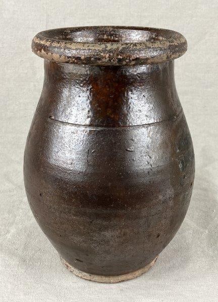 Redware Crock: A redware crock with a rounded form and an incised ring detail near the rim, displaying traditional utilitarian character. Measures approximately 10″ H x 6 1/2″ W. Shows wear to the glaze