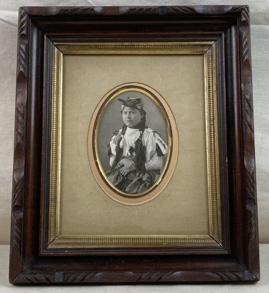 Antique Photograph of Native American Woman: A compelling antique photograph depicting a traditionally dressed young Native American woman, capturing strong period presence and cultural detail. Housed in a decorative wood frame with gilt border