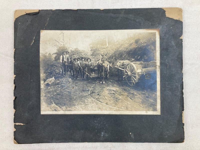 19th Century Photograph of Workers: A handsome 19th-century photograph depicting men posed with donkey-drawn carts along a dirt road. The image retains visible silvering and is mounted on board with a worn, aged patina. Measures approxi
