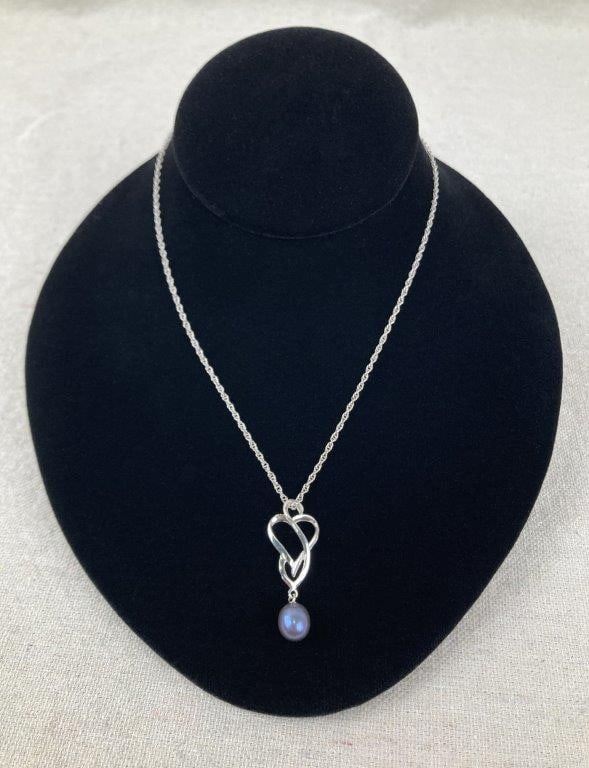 Sterling Silver Pearl Necklace: Sterling silver necklace featuring an abstract heart knot design accented by a dark dangling pearl, offering an elegant and sculptural look. Stamped 925 MF and paired with an 18" chain. Measures
