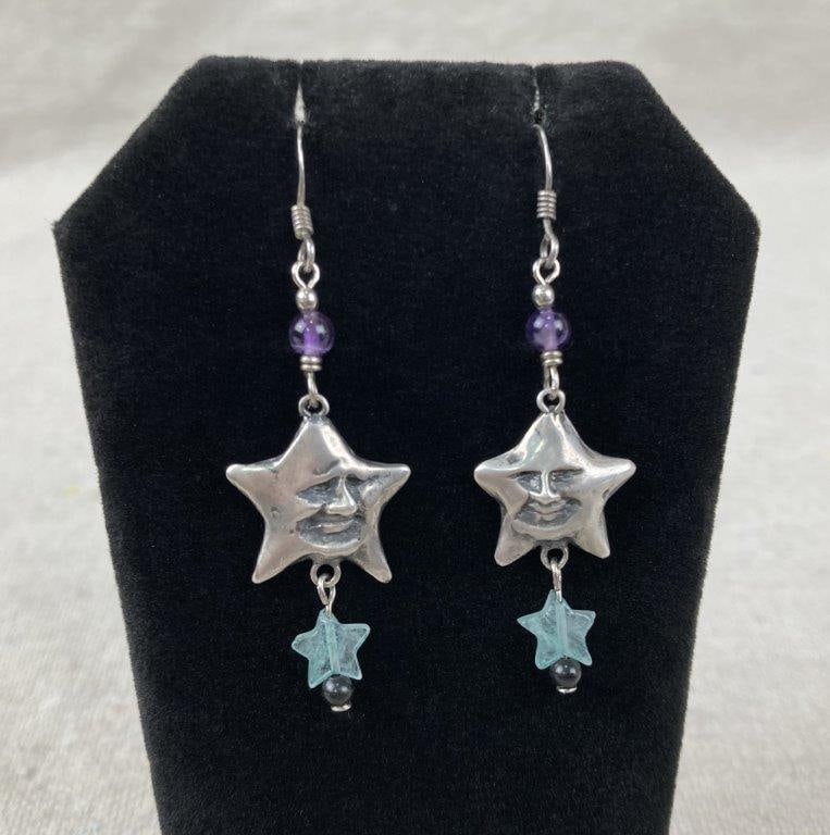 Lucy Isaacs Sterling Silver Celestial Earrings: Sterling silver dangling earrings designed in the form of engraved star faces, each suspending a green glass star with an amethyst bead accent for added color and movement. Stamped LIJ NY S/S. One