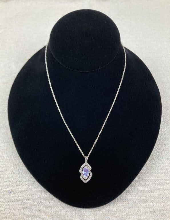 Sterling Silver and Tanzanite Necklace: Sterling silver necklace featuring an oval faceted tanzanite centerpiece framed by clear faceted accent stones, suspended from a fine sterling silver chain. The pendant bears a maker’s mark and