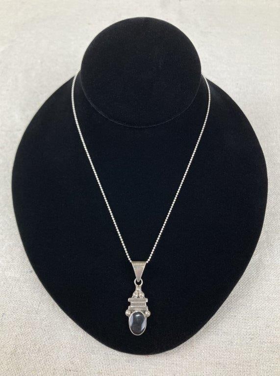 Artisan Sterling Silver and Black Onyx Necklace: Artisan-crafted sterling silver necklace featuring a polished black onyx cabochon set within an intricately worked silver frame, showcasing traditional Mexican silver artistry. Marked Mexico and