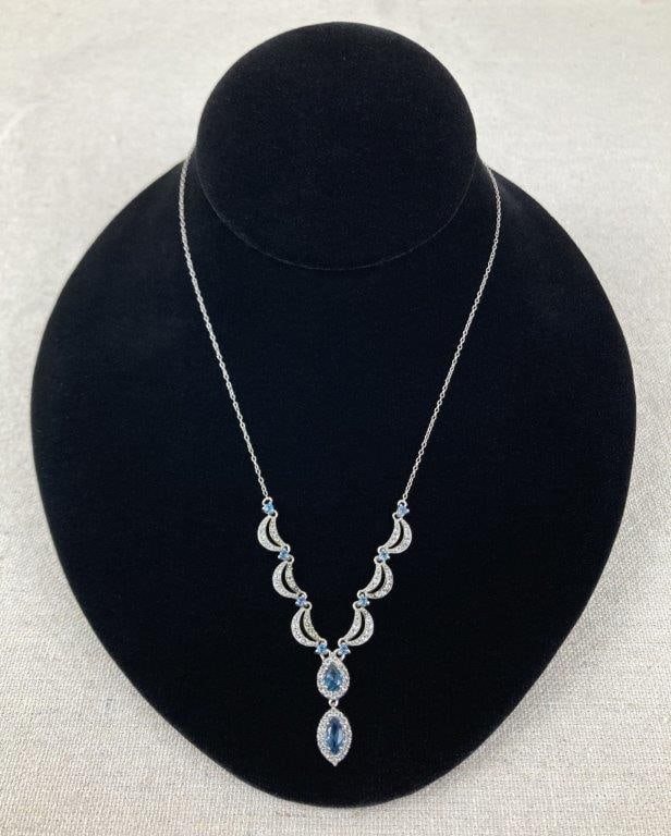 Sterling Silver and Blue Topaz Necklace: Sterling silver necklace featuring likely blue topaz stones, each surrounded by a halo of clear, faceted accent stones in a classic, elegant design. Marked 925 for sterling silver, with an additional