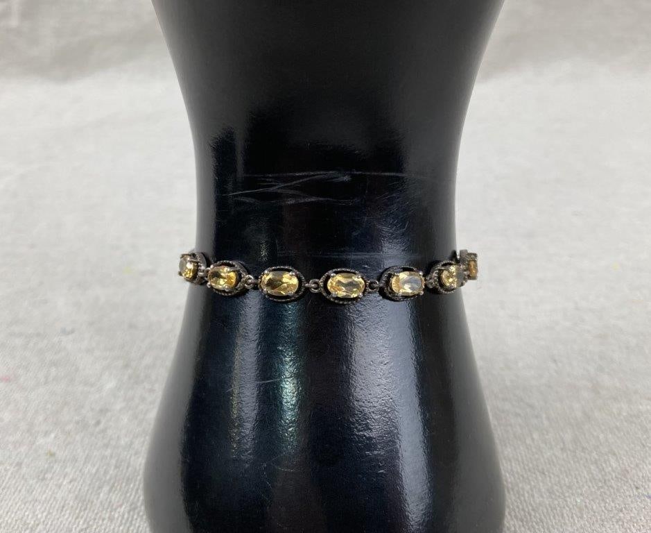 Sterling Silver and Yellow Citrine Slider Bracelet: Sterling silver slider bracelet featuring oval faceted yellow citrine stones set along the bracelet, finished with an adjustable bolo-style clasp. The bracelet is primarily sterling silver, with the