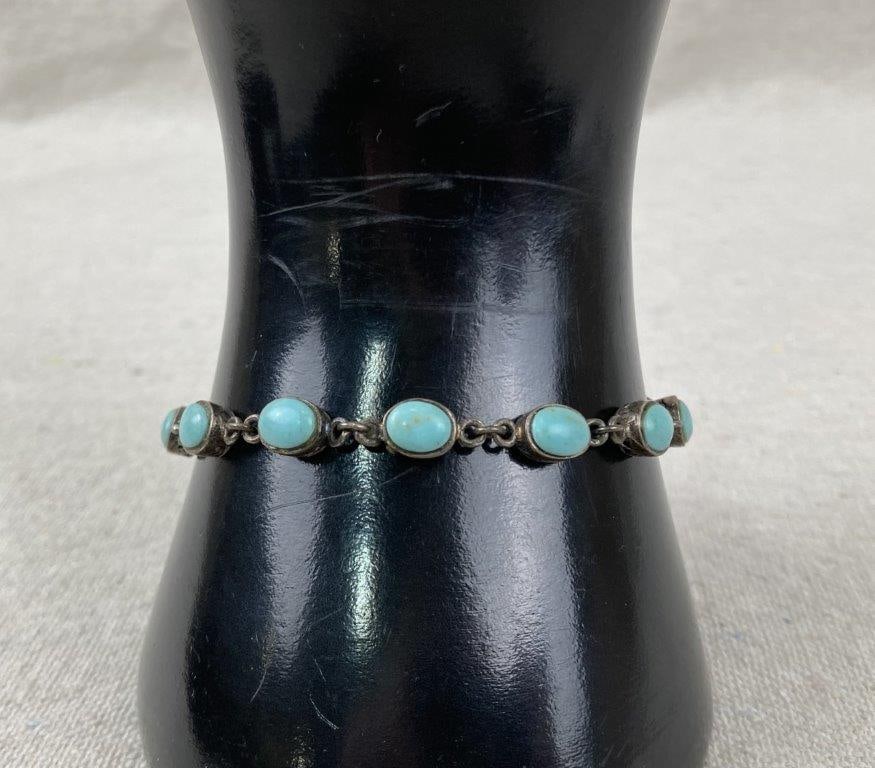 Sterling Silver and Turquoise Bracelet: Sterling silver bracelet featuring oval turquoise cabochons set within raised openwork filigree bezels, joined by an interconnected chain. Marked 925 on the interior of the box clasp. Measures