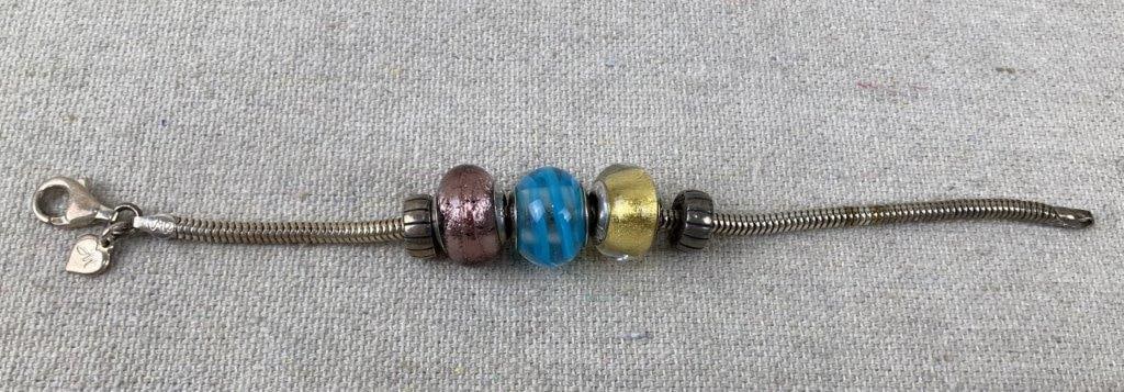 Sterling Silver Murano Art Glass Bead Bracelet: Sterling silver bracelet featuring three Murano art glass beads in pink, blue, and gold, accented with sterling silver bead caps and spacer details. Designed on a sterling silver snake chain with two