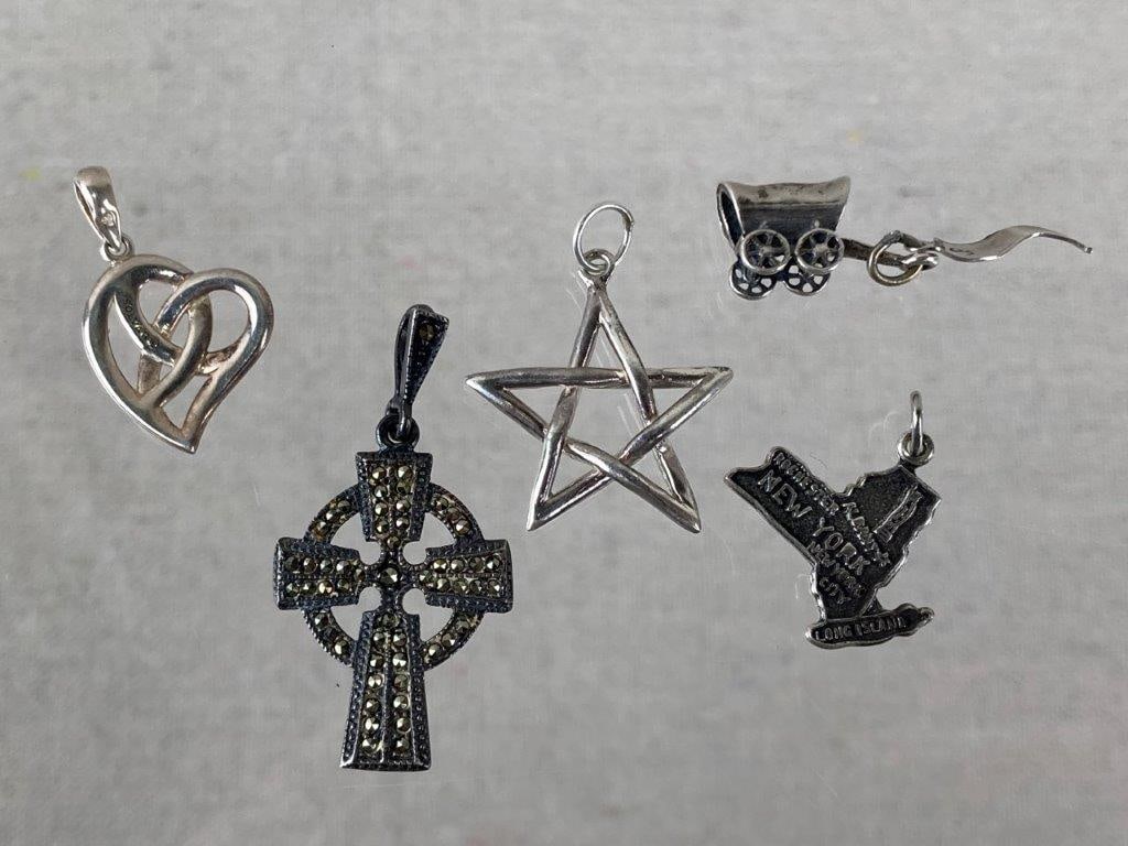 Collection of Sterling Silver Charms: Collection of sterling silver charms in a variety of forms and themes, including a New York map stamped Sterling, a covered wagon with a dangling Tucson, Arizona banner stamped Sterling, a five-pointe
