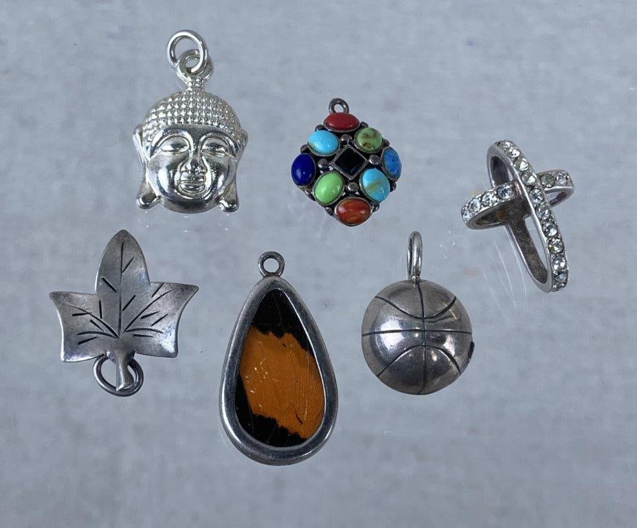 Collection of Sterling Silver Charms: Collection of sterling silver charms in varied forms and finishes, including a cross set with clear stones stamped 925 C, a butterfly wing section encased in glass and sterling stamped 950, a