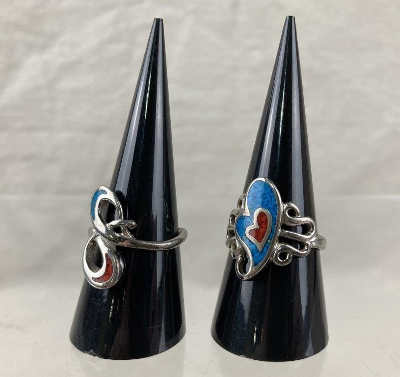 Southwestern-Style Silvertone Ring Pair: Pair of Southwestern-style silvertone rings featuring turquoise- and coral-style inlay arranged in swirling, decorative patterns. Both rings are size 9. In good condition with light wear consistent