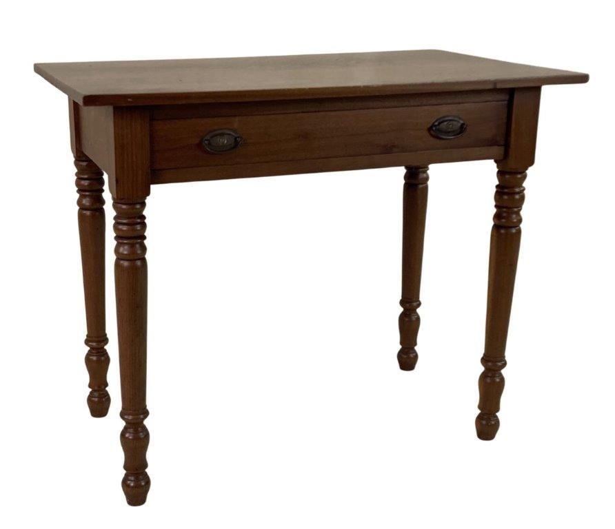 19th Century One Drawer Stand: A 19th century walnut stand featuring turned legs and a single drawer fitted with handsome brass pulls. The piece retains a rich, dark patina that enhances the warmth and character of the wood.