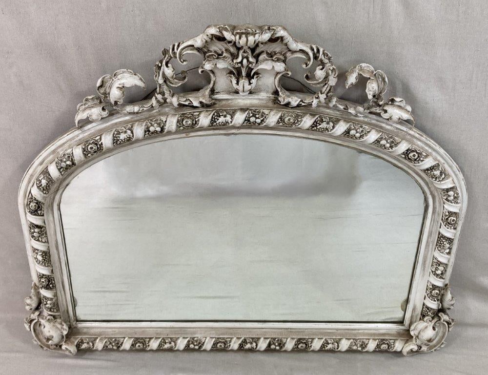 Louis XV Carved Mirror: A Louis XV style carved mirror in white paint, featuring a shaped arch crest adorned with shell and acanthus ornament above a spiral-carved border enriched with fruit and floral reserves. The
