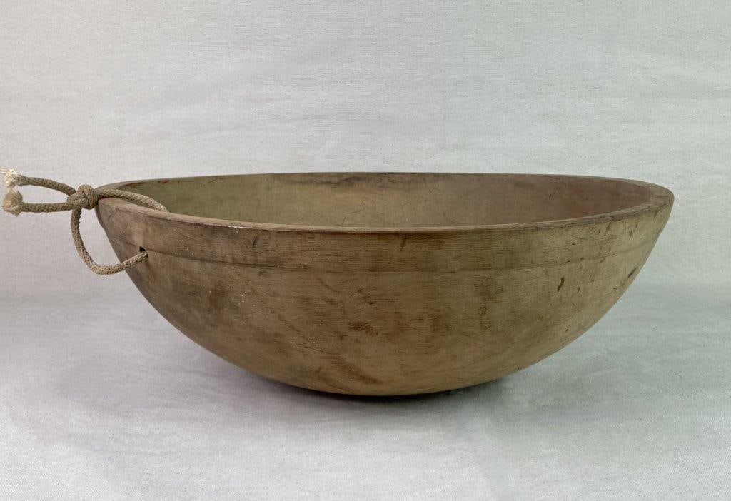 Munising Wood Dough Bowl: A hand-turned wooden dough bowl by Munising Wood Products Co., featuring a rope threaded through the rim on one side. Exhibits a worn, aged patina from use and handling. Measures approximately 6
