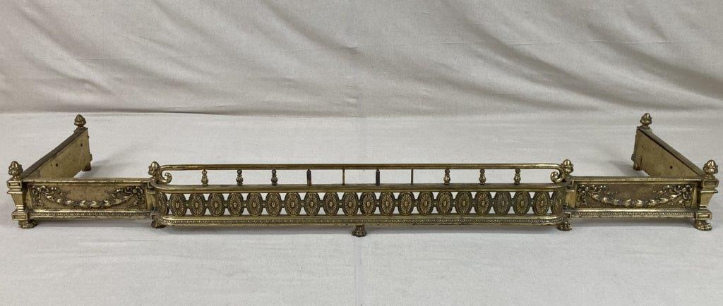 Neoclassical Style Brass Fireplace Fender: A Neoclassical style brass fireplace fender featuring columnar supports and decorative swag detailing, presenting a refined and architectural hearthside presence. The elongated form and balanced