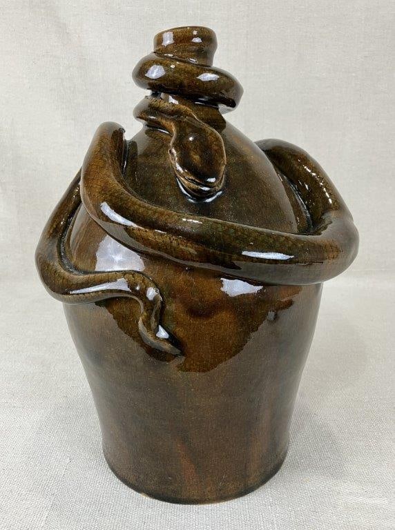Marvin Bailey Snake Stoneware Jug: A striking stoneware jug featuring a snake depicted in relief, coiled around the upper portion of the vessel. The surface is finished in a rich brown glaze with sienna highlights that accentuate the