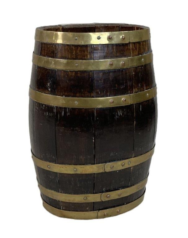 English Brass-Bound Barrel: An antique English barrel constructed of coopered oak staves and secured with six brass bands. Exhibits a worn, aged patina. Measures approximately 22 3/4″ H x 14 1/4″ W x 11″ D. In