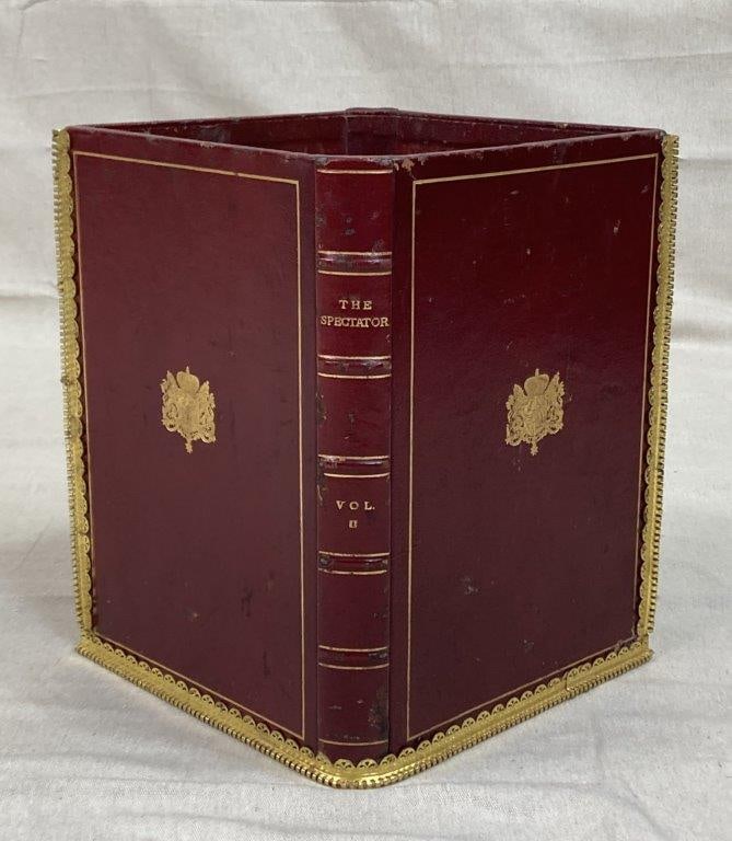 Leatherbound “The Spectator” Book Wastepaper Basket: A decorative wastepaper basket designed in the form of antique leather-bound books, finished in red leather with gold-tone framing. The faux spines are titled The Spectator, marked “VOL