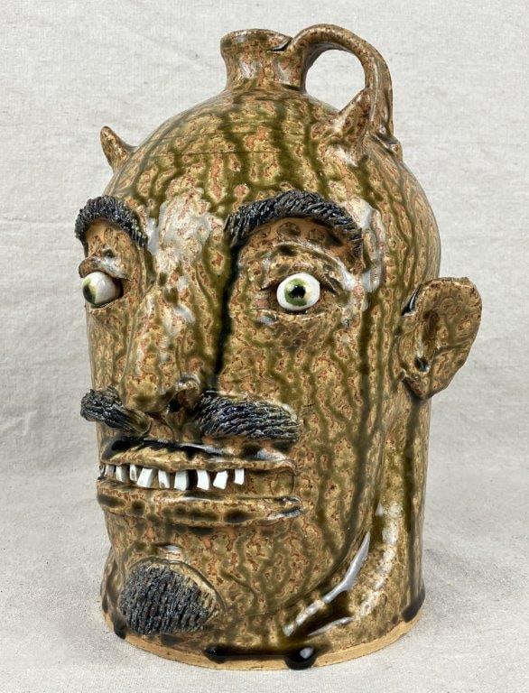 Marvin Bailey Devil Face Jug: A wonderful drip-glaze face jug with a mischievous, expressive visage and applied horned features, further detailed with incised facial hair. Signed “Marvin Bailey” to the underside.