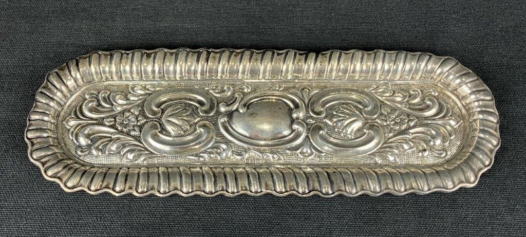 Silverplate Pen Tray: A likely 19th century silverplate pen tray decorated with floral motifs and scrolling ornamentation. Measures approximately 1/4″ H x 9″ W x 3″ D. In good condition with minimal wear