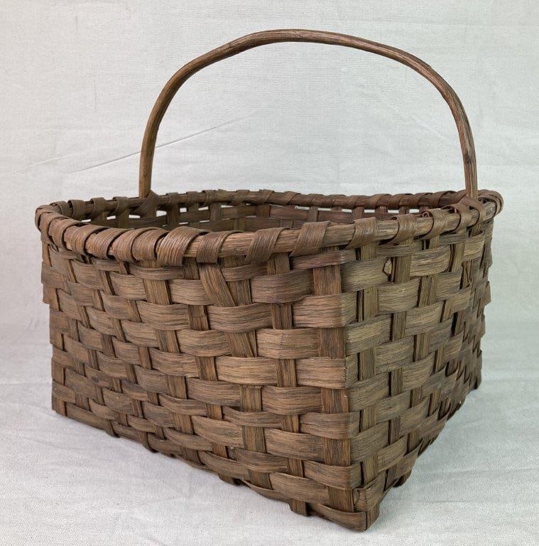 Country Gathering Basket: A split oak country gathering basket with a square base and wrapped rim. Measures approximately 14″ H x 15 1/4″ W x 17 1/2″ D. In good condition with light wear to the surface
