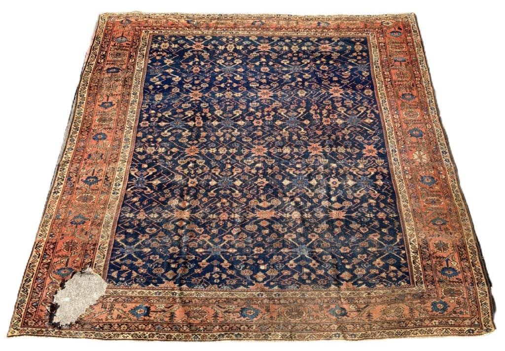 Hand-Knotted Sarouk Rug: A hand-knotted Sarouk rug featuring an all-over floral design set against a rich blue field, framed by a salmon-colored border with repeating floral motifs. The palette and dense patterning create a