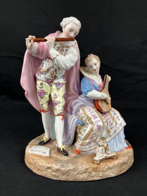 Meissen Porcelain Figurine: A porcelain figurine by Meissen Porcelain, depicting a courtly couple dressed in 18th century Rococo attire. Both playing musical instruments. Rendered in soft pastel tones characteristic of the