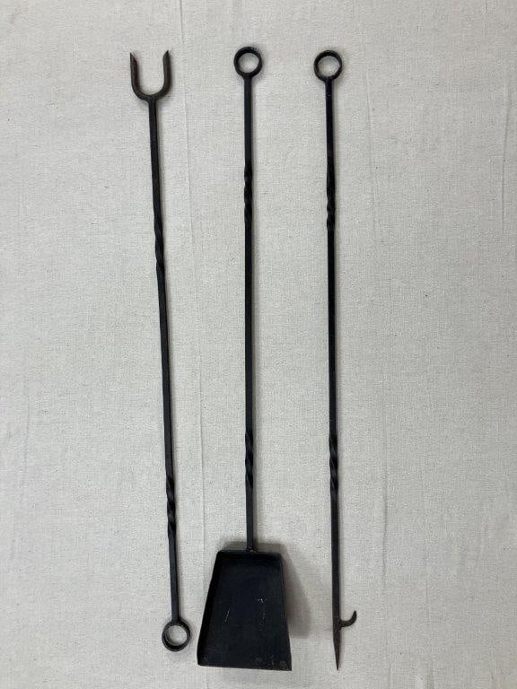 Antique Wrought Iron Fireplace Tools: A set of antique hand-formed wrought iron fireplace tools, exhibiting traditional craftsmanship and utilitarian form. One tool measures approximately 35″ H x 3 3/4″ W x 1″ D. Shows g