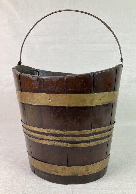 Georgian Mahogany Peat Bucket: A Georgian-period peat bucket constructed of coopered mahogany staves bound with brass brackets, formed in a navette shape and fitted with a brass swing handle. Exhibits a worn, aged patina consistent