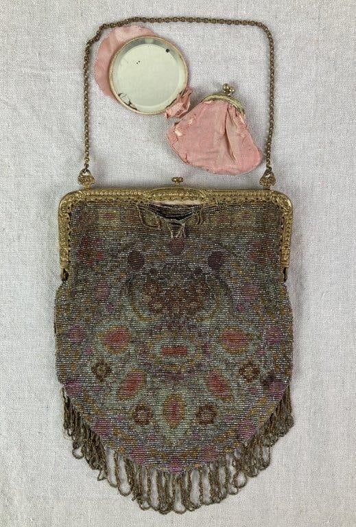 Antique French Glass Bead Purse: An antique French glass bead purse featuring a decorative gold-tone steel filigree frame and a multicolored floral beaded pattern. Finished with a beaded fringe along the bottom and retaining an inter