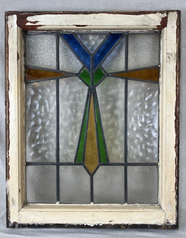 Stained Glass Window: A stained glass window featuring a bold geometric cross motif reflective of Art Deco design sensibilities. The colored glass panels are set within a distressed wood frame retaining softly toned