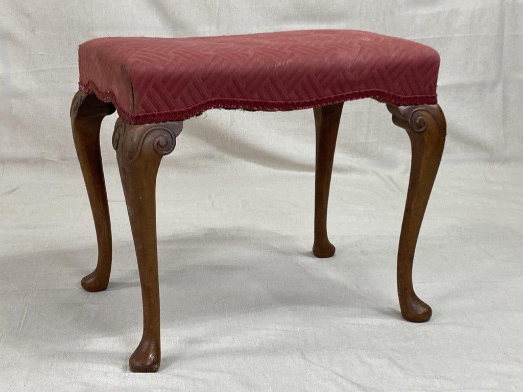 Antique English Mahogany Stool: A Georgian-style English stool with an elegant mahogany frame and graceful cabriole legs. Upholstered in red fabric featuring a repeating linear pattern. Exhibits an aged patina to the wood. Measures