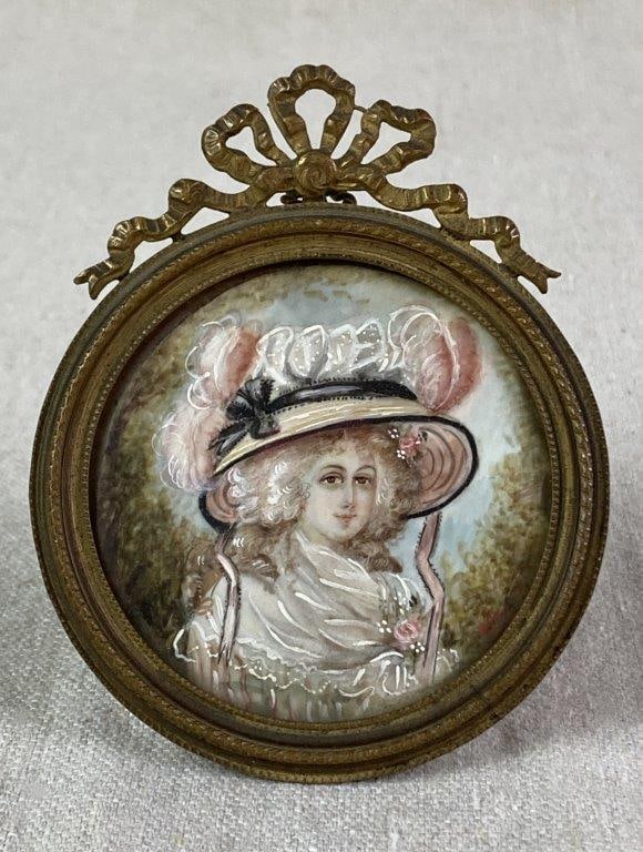 19th Century Miniature Portrait of Woman: A hand-painted miniature portrait depicting an aristocratic lady wearing a large feather-adorned hat. Signed by the artist at the lower right. Set within a neoclassical metal frame with an easel