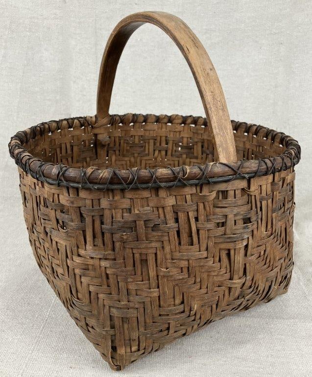 Gathering Basket: A gathering basket with a warm, mellowed patina and wrapped rim. Measures approximately 12″ H x 10 5/8″ W x 11 1/4″ D. Shows some breaks and general wear consistent with age and