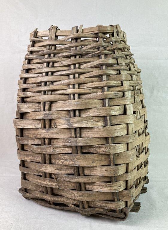 Antique Country Gathering Basket: An antique country gathering basket woven with thick split oak splints, featuring a square base and sturdy utilitarian form. Exhibits a worn, aged patina from use. Measures approximately 18 1/2″