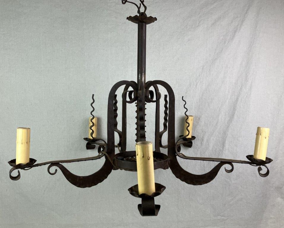 Iron Spanish Revival Chandelier: A handwrought iron chandelier in the Spanish Revival style, showcasing expert forged ironwork and traditional craftsmanship. Measures approximately 21″ H x 29″ in diameter. Shows general w