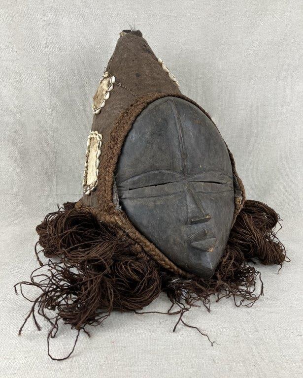 West African Dan Mask: A sacred ceremonial mask from the Dan people, believed to embody spiritual presence rather than merely represent it. Hand-carved and stained with a dark dye, the mask features narrow slitted eyes
