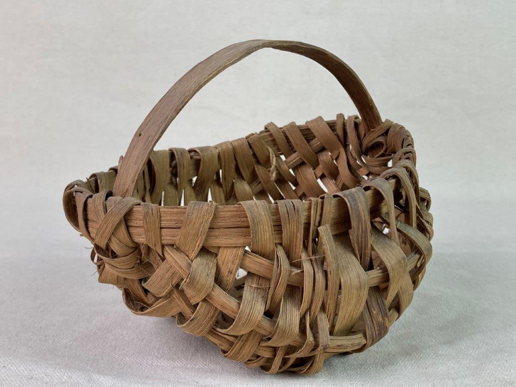 Small Country Buttocks Basket: A split oak buttocks basket with a wrapped rim and a worn, mellowed patina. Measures approximately 5â€³ H x 6â€³ W x 5â€³ D. Shows some wear to the